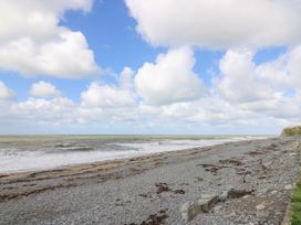 A rocky beach with seaweed patches under a cloudy sky at D12 Treetops Clarach near Aberystwyth