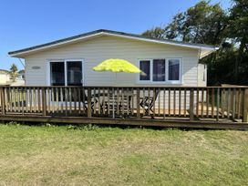A cabin with a deck and an umbrella at Chalet 3 Wipeout in Hayle