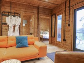 A living room with a sofa and robes hanging at Bee Hive South Luffenham near Edith Weston