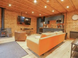A living room with a sofa, armchair, and kitchen area at Bee Hive in South Luffenham near Edith Weston