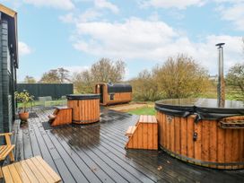 An outdoor area with wooden hot tub, sauna, and seating at Bee Hive in South Luffenham near Edith Weston