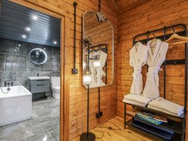 A bathroom with a bathtub and towels in a wooden cabin at Rabbit Hole near Stamford