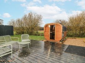 An outdoor area with a wooden sauna and chairs at Rabbit Hole near Stamford