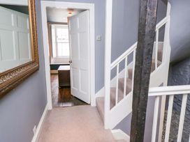 A hallway with a staircase and a door at Unicorn Cottage