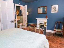 A bedroom with a bed and a door leading to a bathroom at Unicorn Cottage