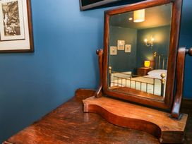 A mirror reflecting a bed and lamp at Unicorn Cottage