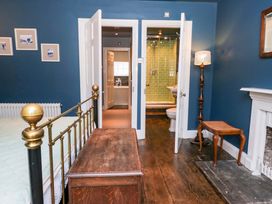 A bedroom with a bed, light fixture, and bathroom access at Unicorn Cottage