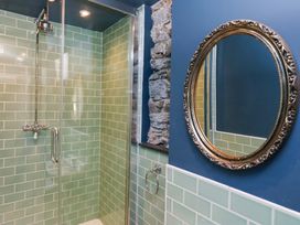 A bathroom with a shower and a round mirror at Unicorn Cottage