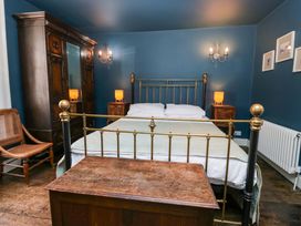 A bedroom featuring a brass bed and wooden furniture at Unicorn Cottage