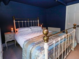 A bedroom with a bed and nightstand at Unicorn Cottage