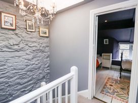 A hallway with a chandelier and stone wall at Unicorn Cottage