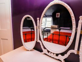 A mirror with a bed and window in view at Unicorn Cottage