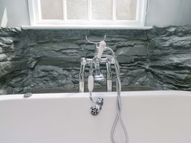 A bath tub with a faucet and shower head at Unicorn Cottage