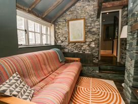 A snug with a striped sofa and stone wall at Unicorn Cottage