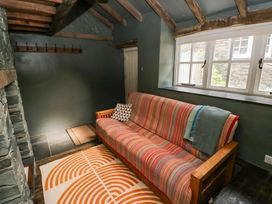 A snug room with a sofa and coat hooks at Unicorn Cottage