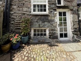 An exterior view showing a stone wall with a door and plants at Unicorn Cottage in Ambleside