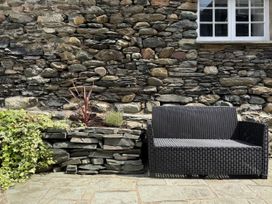 A garden with a stone wall and an outdoor couch at Unicorn Cottage Ambleside