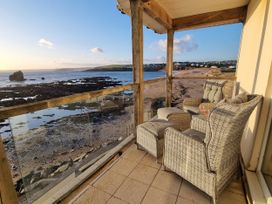 A balcony with chairs and a table overlooking the sea at Sea View Beach Apartment in Thurlestone