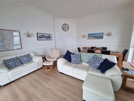A living room with a sofa and dining area at Sea View Beach Apartment in Thurlestone