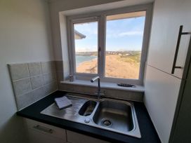 A kitchen with a sink and window overlooking the beach at Sea View Beach Apartment Thurlestone