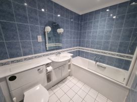 A bathroom with a sink, toilet, bathtub, and mirror at Sea View Beach Apartment Thurlestone