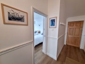 A hallway with artwork and a door leading to a bedroom at Sea View Beach Apartment Thurlestone