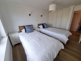 A bedroom with two beds and a wardrobe at Sea View Beach Apartment in Thurlestone