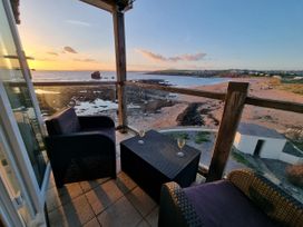A balcony with chairs and a table overlooking the beach at Sea View Beach Apartment Thurlestone