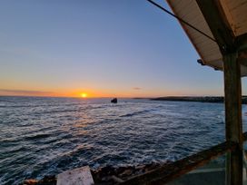 A sunset over the ocean with a rock in the water at Sea View Beach Apartment Thurlestone