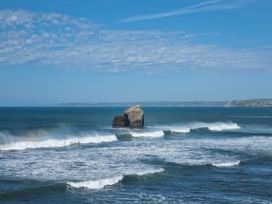A rocky outcrop in the ocean with waves at Sea View Beach Apartment in Thurlestone