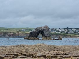 A rock formation in water with houses in the background at Sea View Beach Apartment Thurlestone