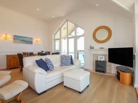 A living room with a sofa, dining table, and television at Seaview Beach Apartment, 11 Thurlestone Rock in Thurlestone