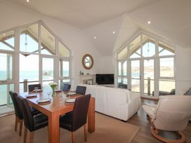 A living room with a dining table and ocean view at Seaview Beach Apartment, 11 Thurlestone Rock in Thurlestone
