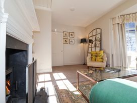 A living room with a fireplace armchair floor lamp glass coffee table and window at Holm Oak Lodge in Tendring near Weeley