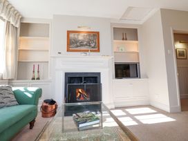 A living room with a green sofa a fireplace a glass coffee table and built-in shelves at Holm Oak Lodge in Tendring near Weeley