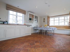 A kitchen and dining area with white cabinets a table with chairs and a built in bench at Holm Oak Lodge in Tendring near Weeley