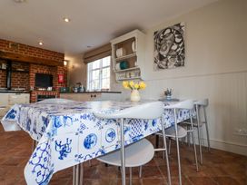 A kitchen with a dining table covered with blue and white tablecloth and chairs at Holm Oak Lodge in Tendring near Weeley