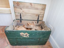 An open green wooden chest filled with firewood on a tiled floor at Holm Oak Lodge in Tendring near Weeley