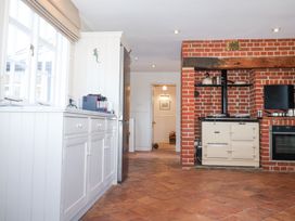 A kitchen with white cabinets a stainless steel refrigerator and a cream stove in a brick alcove at Holm Oak Lodge in Tendring near Weeley