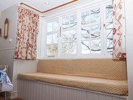 A built in cushioned bench under white framed windows with floral curtains in a room at Holm Oak Lodge Tendring near Weeley