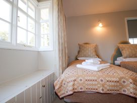 A bedroom with two single beds with patterned blankets and pillows next to a window with curtains at Holm Oak Lodge in Tendring near Weeley