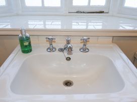 A white bathroom sink with two separate taps and a green liquid soap dispenser on the left at Holm Oak Lodge in Tendring near Weeley