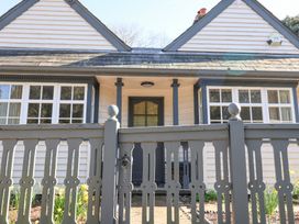 Front view of a house with a grey wooden gate and white windows at Holm Oak Lodge in Tendring near Weeley