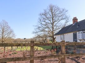 A garden with pruned bushes and a wooden fence near a house with a slate roof and chimneys at Holm Oak Lodge in Tendring near Weeley