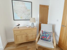 An entryway with a chest of drawers and an armchair at 36 Parc Delfryn
