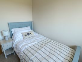 A bedroom with a bed, bedside table, and lamp at 36 Parc Delfryn