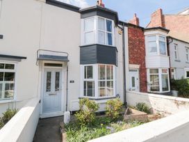 A row of terraced houses with a small garden and a pathway leading to a front door at Tulip Cottage in Staithes