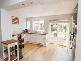 A kitchen with white cabinets wooden countertops a sink an oven a microwave and sliding glass doors leading to a garden at Tulip Cottage in Staithes