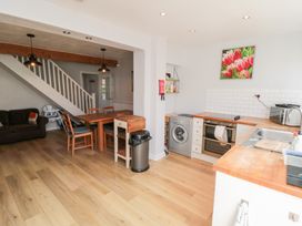 A kitchen and dining area with wooden table and chairs washing machine oven and sink at Tulip Cottage in Staithes