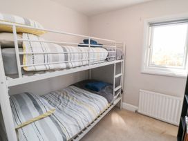 A small bedroom with a white bunk bed near a window and radiator at Tulip Cottage in Staithes